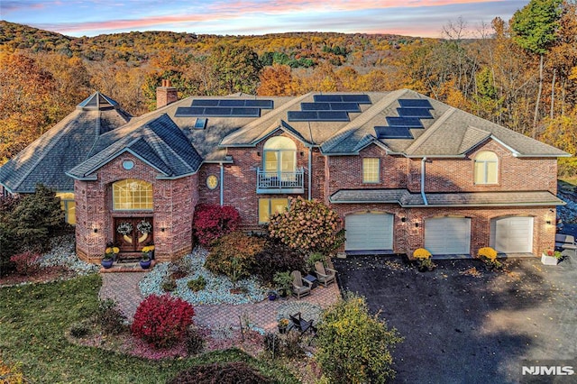 view of front of property featuring solar panels, a garage, and a balcony