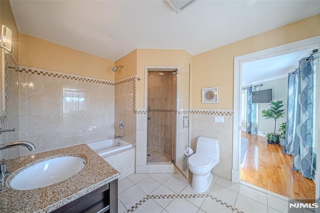 bathroom with tile patterned floors, vanity, toilet, and tile walls