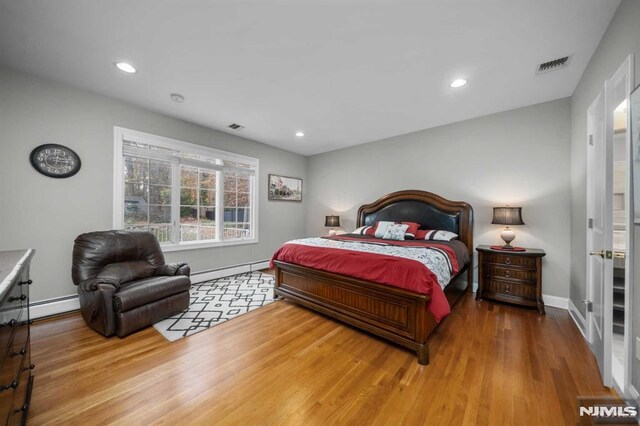 bedroom featuring wood-type flooring and a baseboard radiator