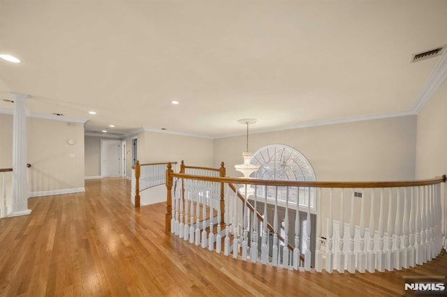 hall featuring a chandelier, wood-type flooring, and ornamental molding