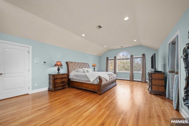 bedroom featuring baseboard heating, light hardwood / wood-style floors, and lofted ceiling