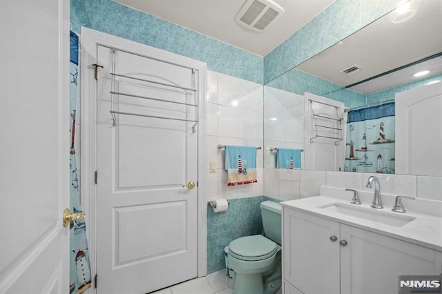 bathroom featuring vanity, tile patterned flooring, toilet, tile walls, and walk in shower