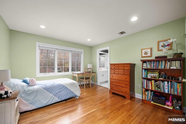 bedroom with ensuite bath and light wood-type flooring