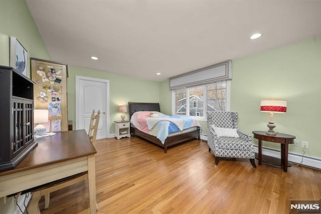 bedroom with baseboard heating and light hardwood / wood-style floors