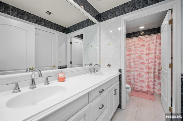 bathroom featuring tile patterned floors, vanity, walk in shower, and tile walls