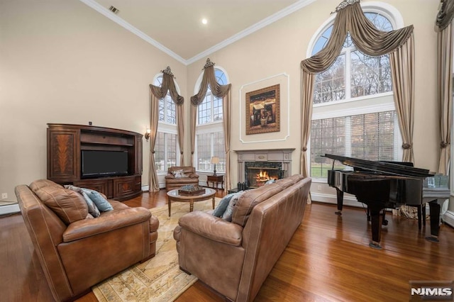 living room with a fireplace, wood-type flooring, crown molding, and a high ceiling