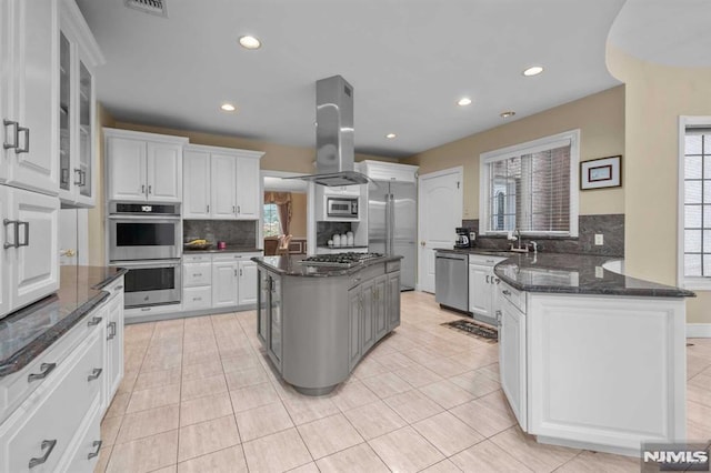 kitchen with a center island, decorative backsplash, white cabinetry, island exhaust hood, and stainless steel appliances