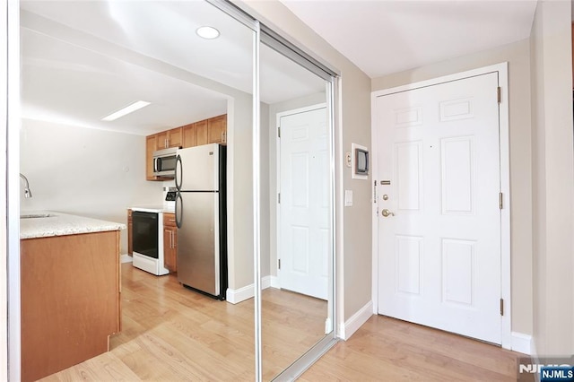 kitchen featuring stainless steel appliances, sink, and light hardwood / wood-style flooring