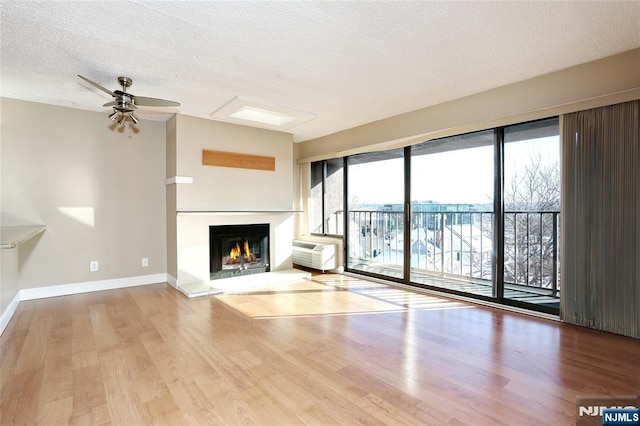 unfurnished living room featuring ceiling fan, a textured ceiling, and light wood-type flooring