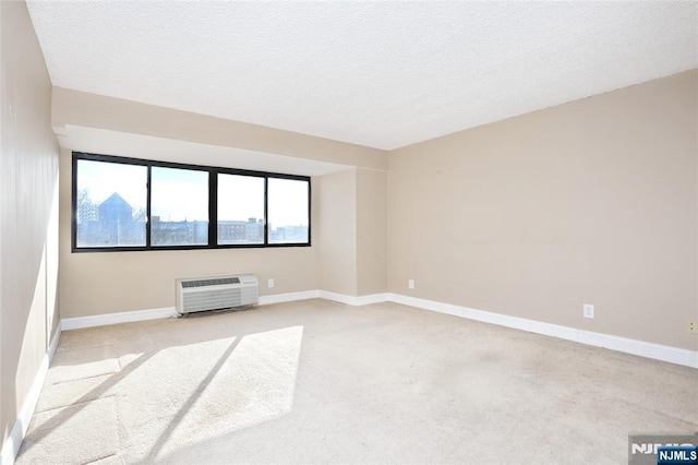 carpeted empty room with a wall unit AC and a textured ceiling