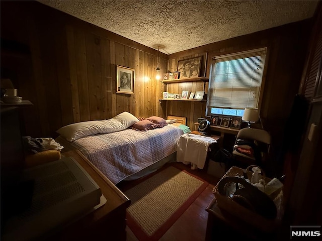 bedroom featuring a textured ceiling and wooden walls