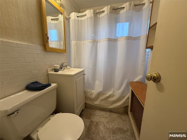 bathroom with tile walls, toilet, vanity, and a shower with shower curtain