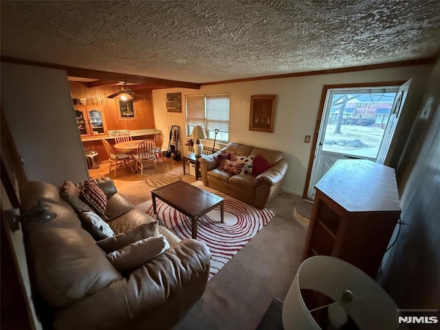 living room featuring ceiling fan, a healthy amount of sunlight, wooden walls, and a textured ceiling