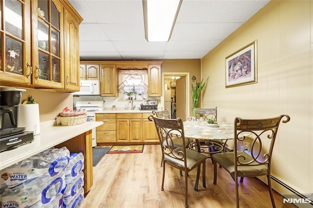 kitchen with a drop ceiling, light wood-type flooring, white appliances, and sink