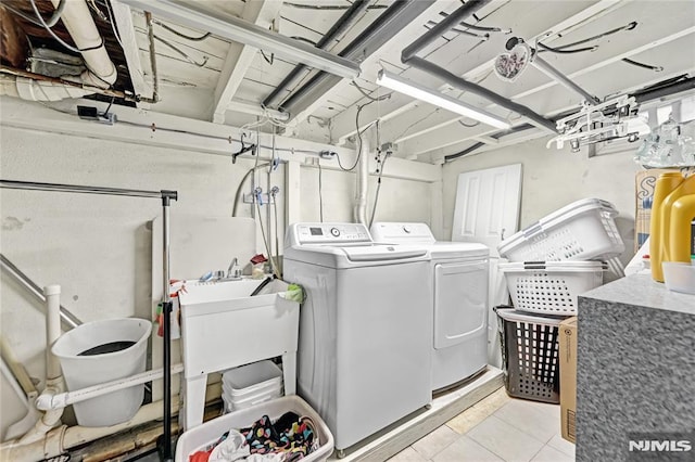 washroom with washer and clothes dryer, light tile patterned flooring, and sink