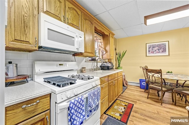 kitchen with a drop ceiling, white appliances, sink, light wood-type flooring, and a baseboard radiator