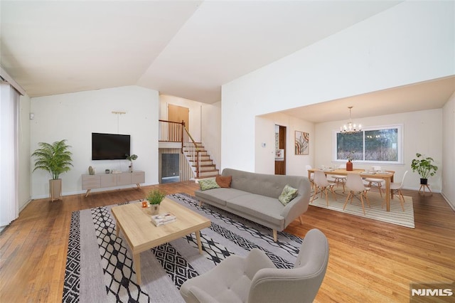 living room featuring vaulted ceiling, a chandelier, and light wood-type flooring