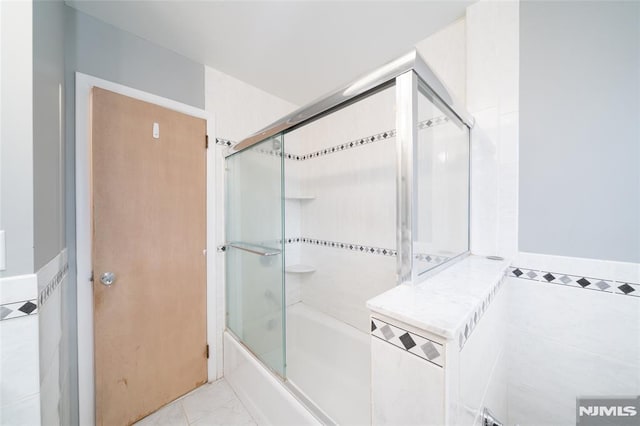 bathroom featuring bath / shower combo with glass door, tile walls, and tile patterned floors