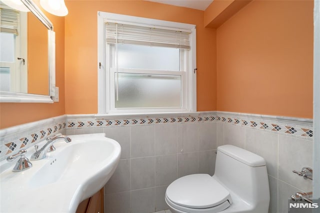 bathroom with toilet, vanity, and tile walls