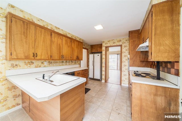 kitchen with a breakfast bar, kitchen peninsula, sink, stovetop, and white refrigerator