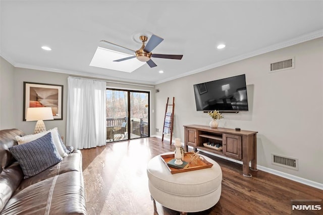 living room with ceiling fan, a skylight, dark hardwood / wood-style floors, and ornamental molding