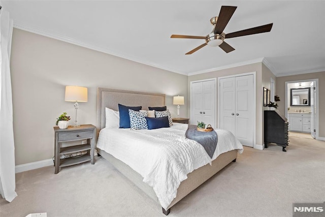 carpeted bedroom featuring ceiling fan, connected bathroom, ornamental molding, and multiple closets