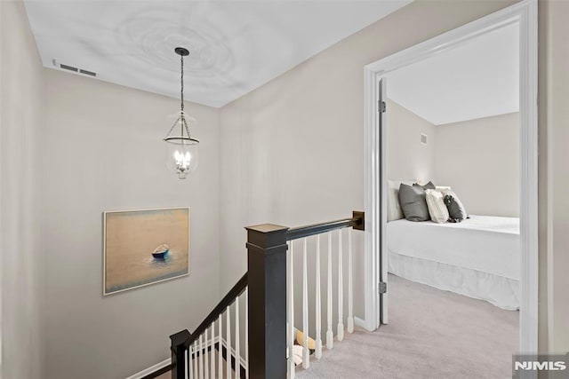 hallway featuring light colored carpet and a chandelier