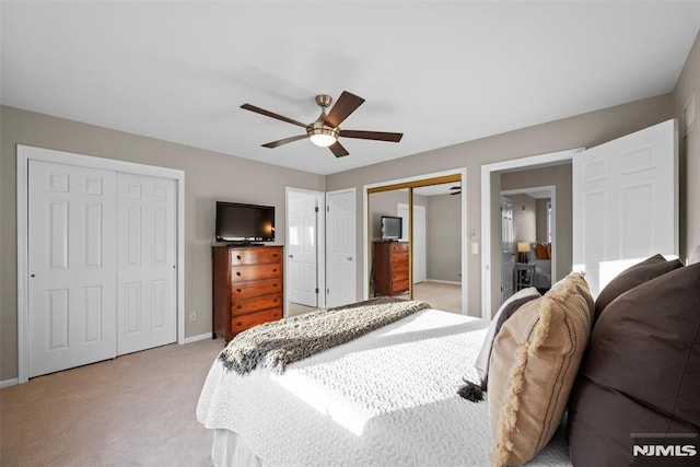 carpeted bedroom with ceiling fan and two closets