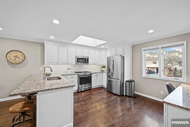 kitchen featuring stainless steel appliances, white cabinets, and kitchen peninsula