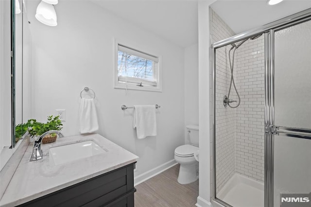 bathroom featuring toilet, vanity, a shower with shower door, and hardwood / wood-style floors