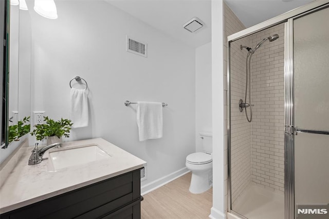 bathroom featuring toilet, vanity, wood-type flooring, and a shower with shower door