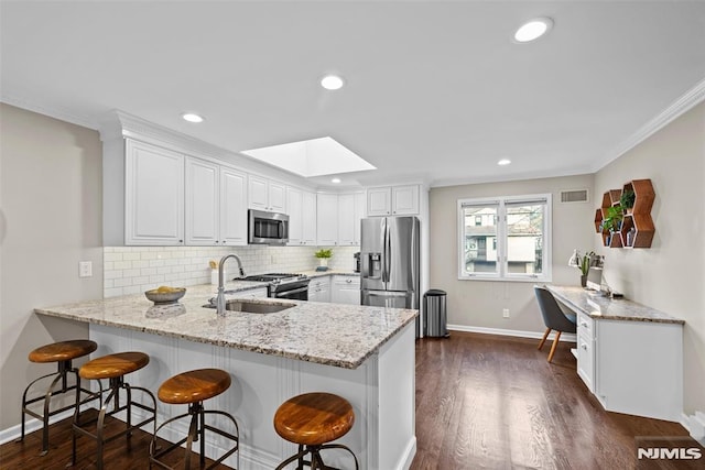 kitchen with kitchen peninsula, sink, stainless steel appliances, and white cabinetry