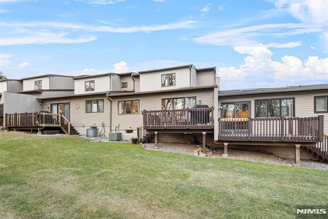 rear view of house with central air condition unit, a deck, and a yard