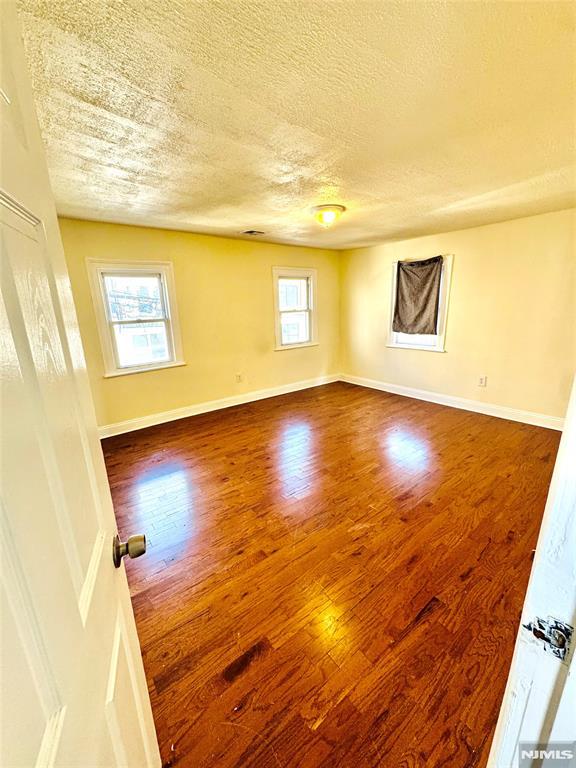 unfurnished room with hardwood / wood-style floors, a healthy amount of sunlight, and a textured ceiling