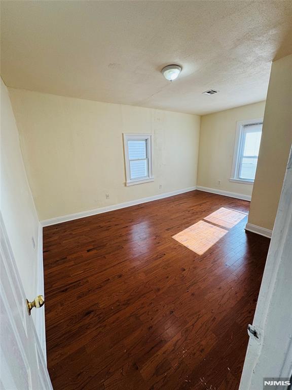 spare room with dark wood-type flooring and a textured ceiling