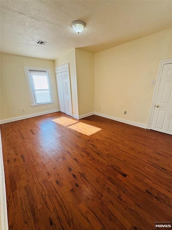 empty room with wood-type flooring and a textured ceiling