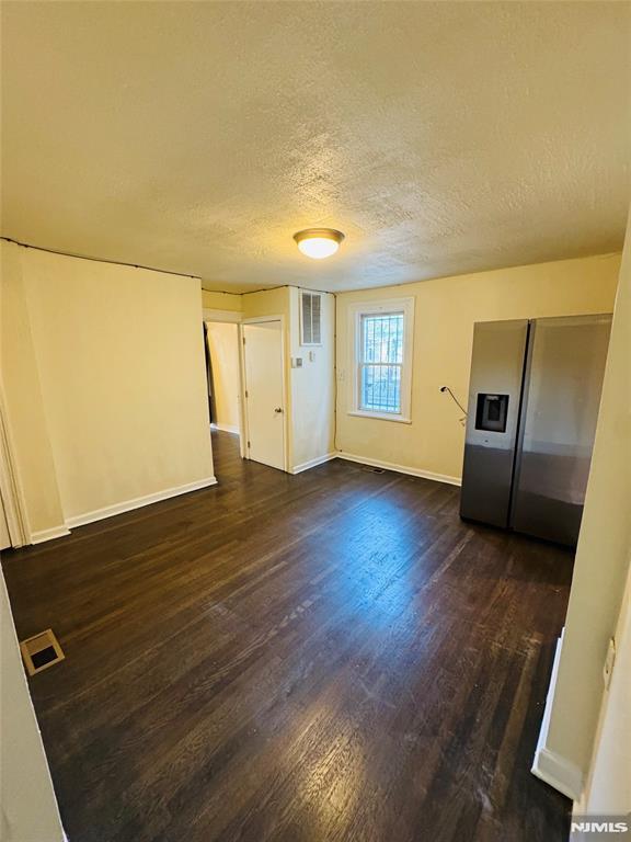 empty room with a textured ceiling and dark hardwood / wood-style floors