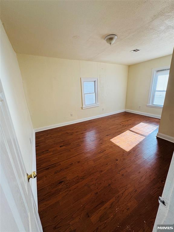 unfurnished room with dark hardwood / wood-style flooring and a textured ceiling