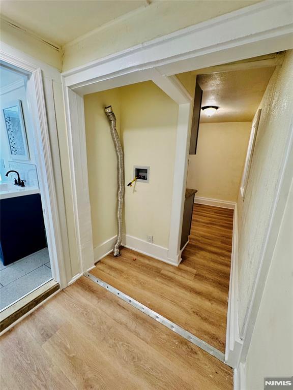 clothes washing area with hardwood / wood-style floors, washer hookup, and sink