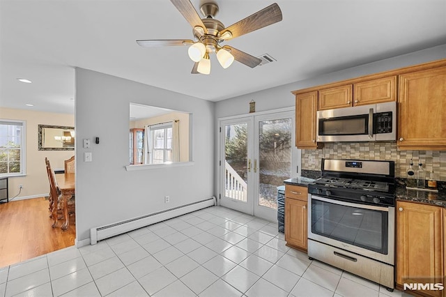 kitchen with appliances with stainless steel finishes, french doors, dark stone counters, baseboard heating, and light tile patterned floors