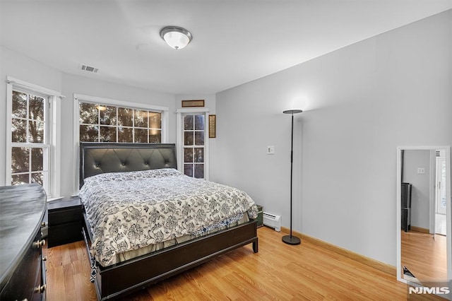 bedroom with hardwood / wood-style floors and a baseboard radiator