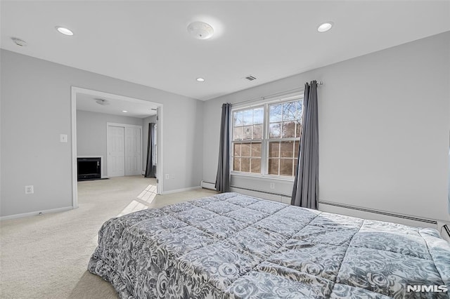 bedroom featuring light carpet and a baseboard heating unit