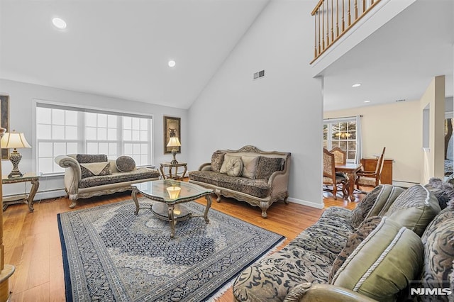 living room featuring hardwood / wood-style flooring, high vaulted ceiling, and a baseboard heating unit