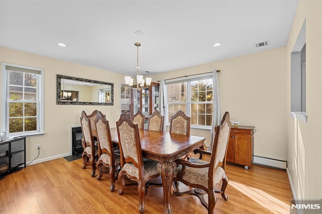 dining space featuring baseboard heating, light hardwood / wood-style flooring, and a chandelier