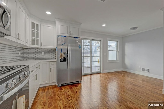 kitchen featuring ornamental molding, stainless steel appliances, white cabinetry, and backsplash