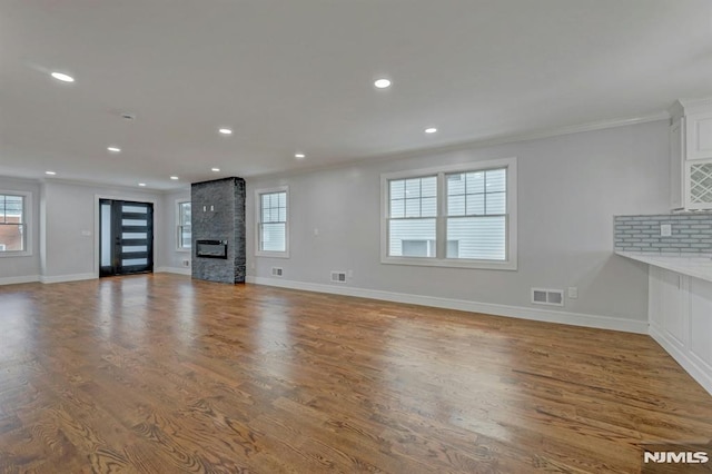 unfurnished living room with hardwood / wood-style flooring, crown molding, and a fireplace