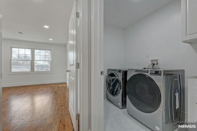 laundry room with washing machine and dryer and cabinets