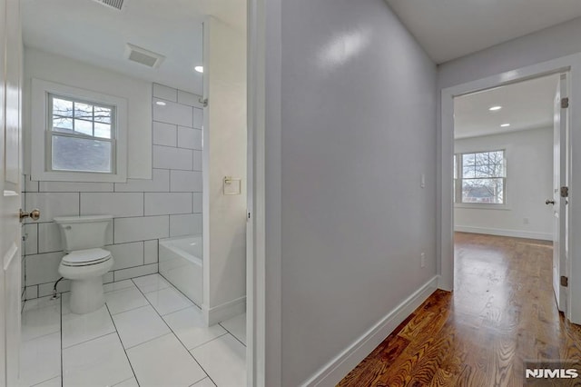 bathroom featuring toilet, wood-type flooring, and tile walls