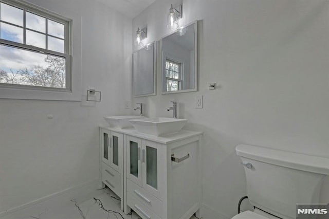 bathroom with toilet, vanity, and a healthy amount of sunlight