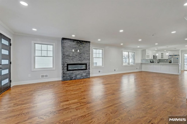 unfurnished living room featuring light hardwood / wood-style floors, crown molding, and a fireplace